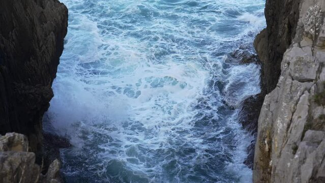 Breathtaking view of rough rocky cliff near calm sea on Ribadesella coast under gray sky in Asturias