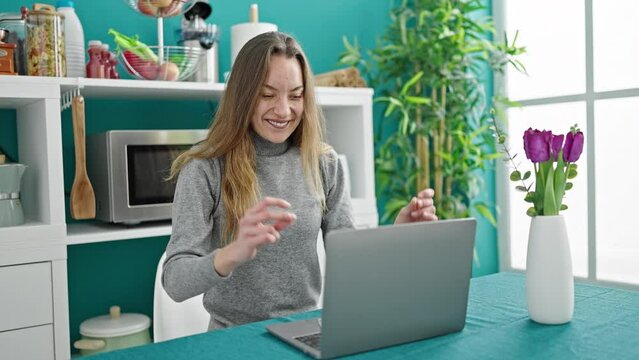 Young caucasian woman using laptop with winner expression at dinning room