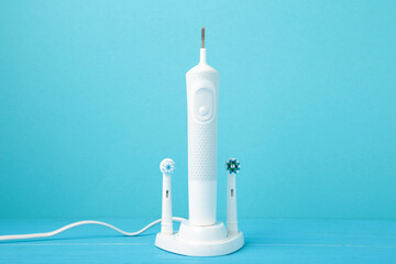 Modern electric toothbrush with charger on blue background