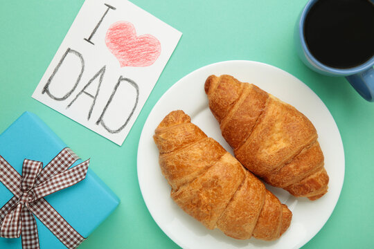 Father's day concept with gift, card and breakfast on mint. Breakfast for dad with croissant and coffee. - Powered by Adobe