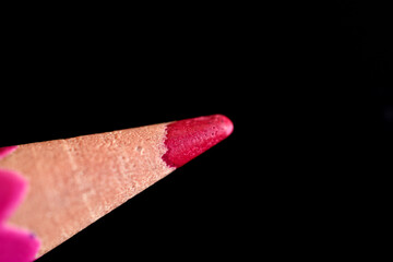 Close-up of a crimson pencil lead against a dark background.