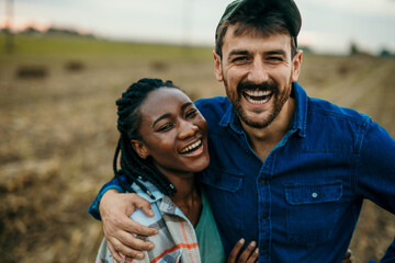 Close up portrait of a diverse couple looking and smiling towards the camera while spending a day outdoors. Lifestyle concept - Powered by Adobe