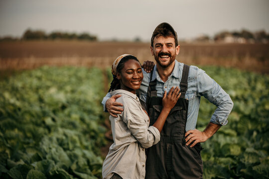 Portrait of two diverse farmers standing in the agricultural field and running their sustainable small business with veggie products.