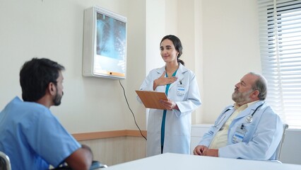 Obraz premium Woman medical assistant talking and explaining the X-ray results of the patient's body and there was an old male doctor sitting there listening at hospital