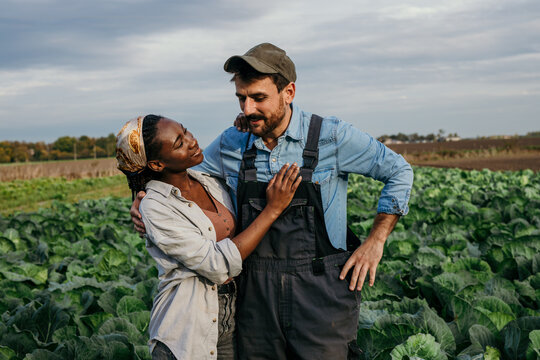 Portrait of a multiracial working couple spending time on their cabbage agricultural land.