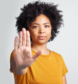 Woman, stop and hand in studio portrait for human rights abuse, racism and afro by gray background. Girl model, gesture or activism for discrimination, justice or protest for freedom, peace or vote