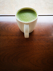 A cup of green tea with milk or hot matcha latte on the wooden table in cafe with copy space    