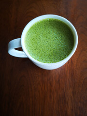 A cup of green tea with milk or hot matcha latte on the wooden table in cafe with copy space    