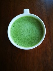 A cup of green tea with milk or hot matcha latte on the wooden table in cafe with copy space    