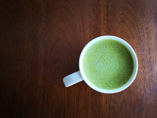 A cup of green tea with milk or hot matcha latte on the wooden table in cafe with copy space    