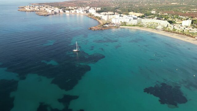 Sailboat Floating On The Calm And Clear Blue Water Of Ocean Near Sa Coma In Mallorca, Spain. - aerial