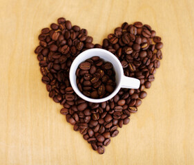 Heart, roasted coffee beans and cafe industry with love icon or emoji for marketing and advertising. Above wooden table or background with grain shape as drink, espresso or caffeine ingredient