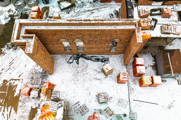 Top view of the construction site. Construction of a red brick house. Building in winter. Detailed shot of the construction site. Snow on the construction site.