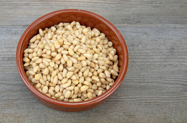 Pine nuts in small brown ceramic bowl