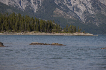 Lake Minnewanka, Banff National Park, Alberta, Canada, in summer - bue cloudy sky, mountains and...