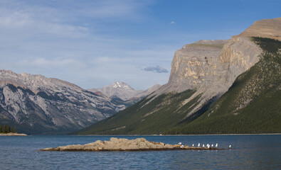 Lake Minnewanka - bue cloudy sky, mountains and clear spring water, Banff National Park, Alberta,...