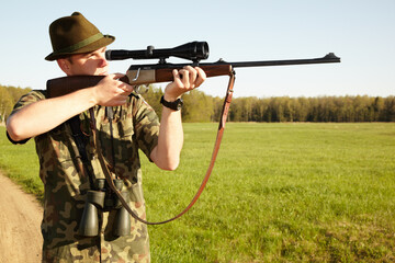 Hunter, gun and man in nature on a Africa safari for animal shooting with a weapon on vacation. Hunting sport, male person and target hunt practise of a traveler in camouflage looking at a scope
