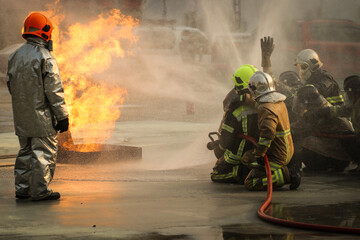 Firefighters using Twirl water fog type fire extinguisher to fighting with the fire flame from oil to control fire not to spreading out. Firefighter and industrial safety concept.