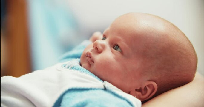 The baby lies on the crib with his eyes open and waves his arms. Cute little boy.