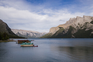 Fototapeta na wymiar Active recreation - canoes, kayaks, boat cruise - tourist point on the lake Minnewanka. Mountain tourism, Banff National Park, Alberta, Canada