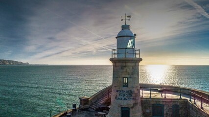 Fototapeta na wymiar The Folkestone Harbour Arm Lighthouse shortly after sunrise.