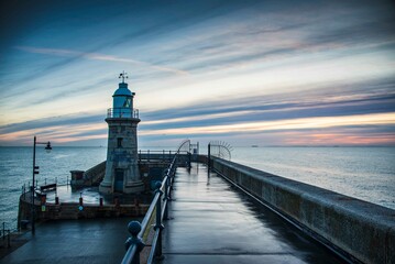 Fototapeta na wymiar Folkestone's Harbour Arm and Lighthouse at dawn.