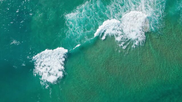 topview zoom out push out of perfect waves at sea washing white waters to shore, mesmerizing wave ocean topview at playa de Tagle, wide oceanic top view in Spain coast.