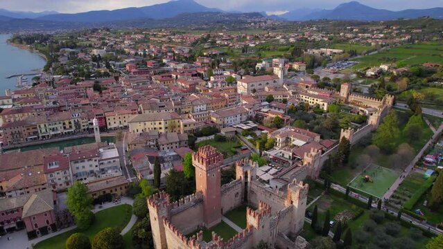 Aerial cinematic dolly out view of Lazise Italian lakeside village illuminated at sunset