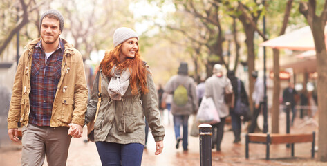 Happy couple, holding hands and walking in city together in winter for romance or travel outdoors....