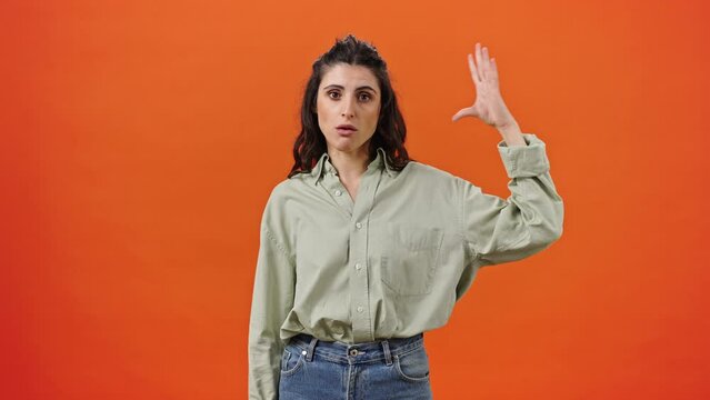 Caucasian young woman shows blah blah blah sign with her hands, boring by gossips, orange background