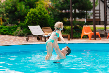Naklejka premium Dad and daughter play in the pool. dad throws daughter in the air.