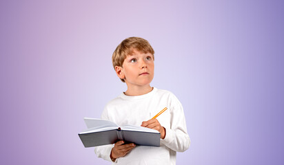 Fototapeta premium Inspired boy taking notes, looking up portrait on purple backgro