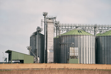 Obraz premium A large grain storage tank with a green roof sits in a field.