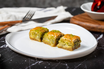 Baklava with pistachio on a dark background. Traditional Turkish baklava. Local name ankara sarmasi. Close up