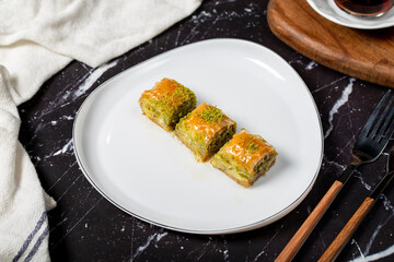Baklava with pistachio on a dark background. Traditional Turkish baklava. Local name ankara sarmasi