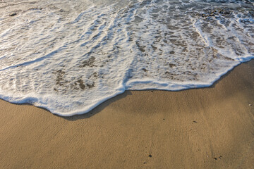 waves with white foam at the fine sand from the beach during sunrise in egypt detail