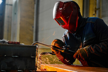 Employee with mask cuts beam with hot gas cutter at plant