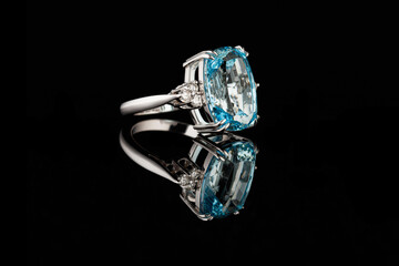 Beautiful gold ring with aquamarine and diamonds on a black background