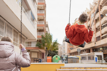 two children ride on a swing with their backs to the camera there is a place for an inscription
