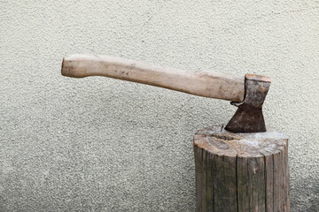 A sharp ax with a wooden handle sticks out in a stump against the background of a dirty textured...