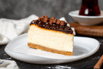 Chocolate cheesecake on dark background. Delicious cheesecake with chocolate chips and cream. Close up