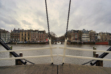 Amsterdam view to one of his many canals standing on bridge holding in position by chains.