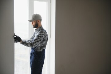 Fototapeta na wymiar Plasterer in blue working uniform plastering the wall indoors