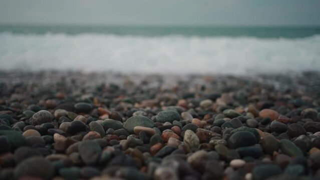 sea or ocean shore with small round pebble stones and water wave, slow motion