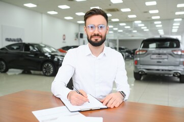 Confident young caucasian businessman shop assistant receptionist working writing at reception desk in car automobile dealer shop