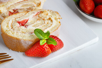 Sweet roll stuffed with strawberry and cream decorated with strawberries, powdered sugar and mint leaves