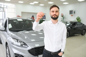 Fototapeta na wymiar Happy young guy checking new luxury car, buying automobile at dealership centre. Portrait of cheerful millennial Caucasian man examining auto at showroom store