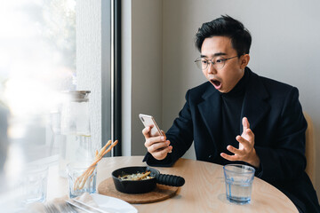 Fototapeta na wymiar Asian businessman is using mobile phone in the restaurant. 