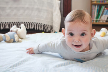 A happy young baby toddler child lying on a play mat looking directly at the camera and smiling -...