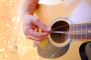 man plays acoustic guitar, close-up hands, strings hanging freely, guitar tuning, concept of...